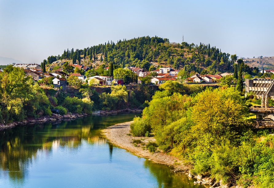 Der Blick auf Podgorica offenbart die idyllische Lage der Stadt am Fluss Morača, umgeben von bewachsenen Hügeln und kleinen Ortschaften.