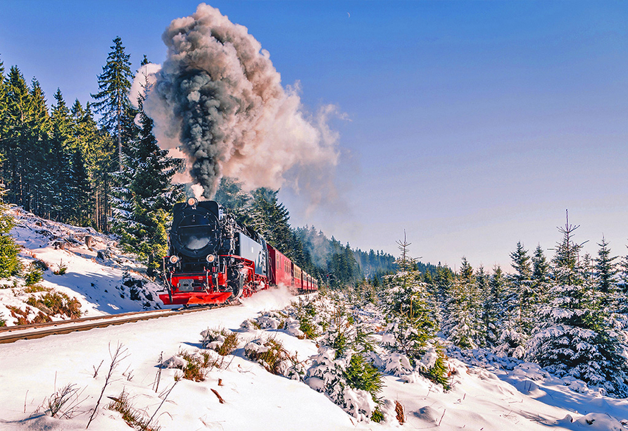 Die Brockenbahn schlängelt sich in leuchtendem Rot durch die weiße Winterlandschaft.