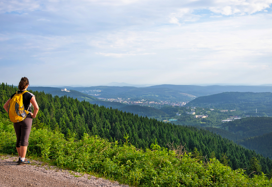 Frau mit Wanderrucksack genießt Ausblick auf Anhöhe.