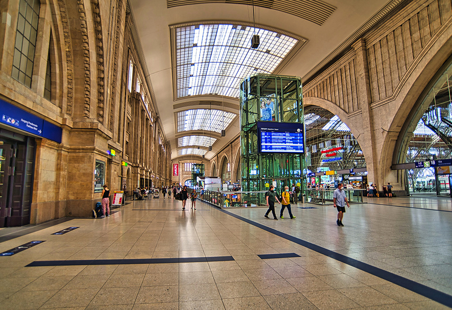 Leipziger Hauptbahnhof und Menschen mit Mundschutzmasken.