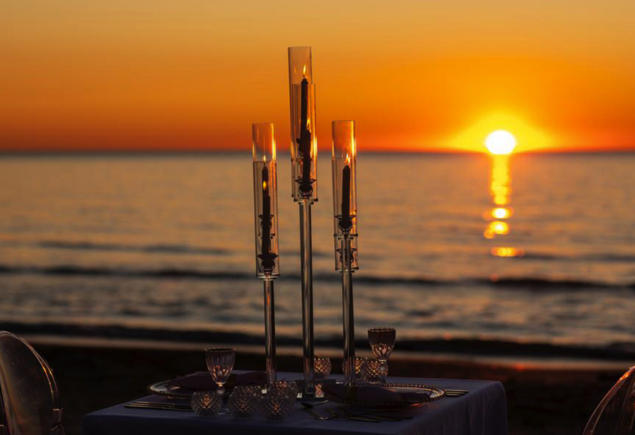 Wie wäre es mit einem Abendessen am Strand mit Blick auf den Sonnenuntergang über dem Meer?