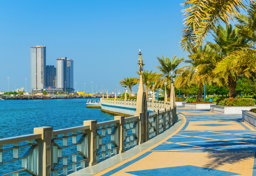 Sie fahren über die Uferstraße Corniche mit Panoramablick auf die Skyline von Abu Dhabi.