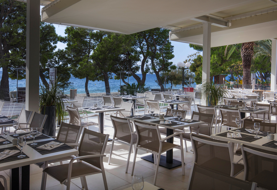 Genießen Sie regionale und internationale Speisen auf der hoteleigenen Terrasse mit Meerblick.