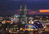 Köln am Abend mit dem Dom und dem Musical Dome, in dem MOULIN ROUGE! Das Musical aufgeführt wird.