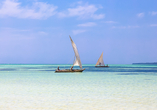Traditionelle Segelboote gleiten über das türkisfarbene Wasser des Diani Beach.