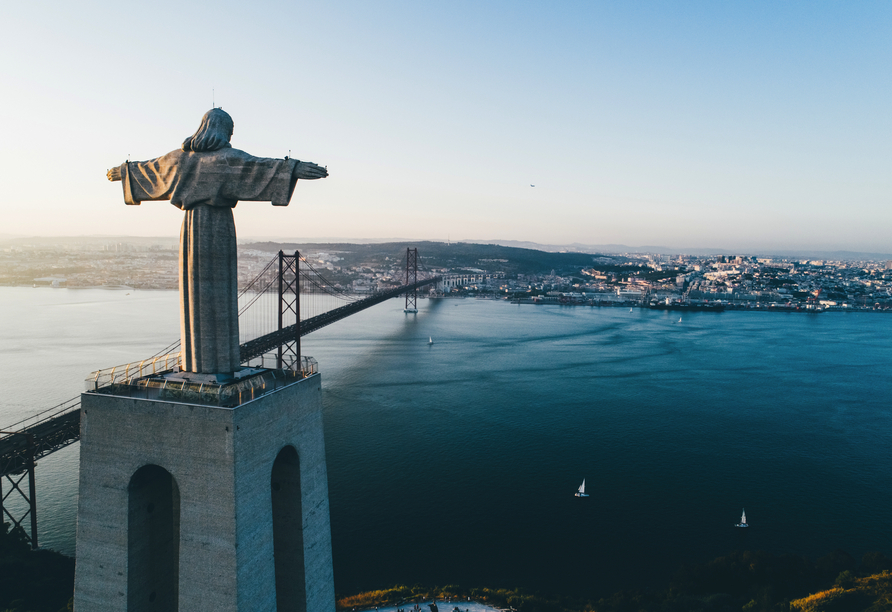 Die Statue Cristo Rei befindet sich rund 117 m über dem Fluss Tejo und blickt auf die Hängebrücke Ponte 25 de Abril.