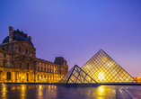 Bei Nacht erstrahlt das Louvre-Museum in goldenem Licht.