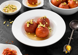 Probieren Sie beliebte indische Speisen und Desserts wie z.B. Gulab Jamun – frittierte, mit Zuckersirup überzogene Teigbällchen.