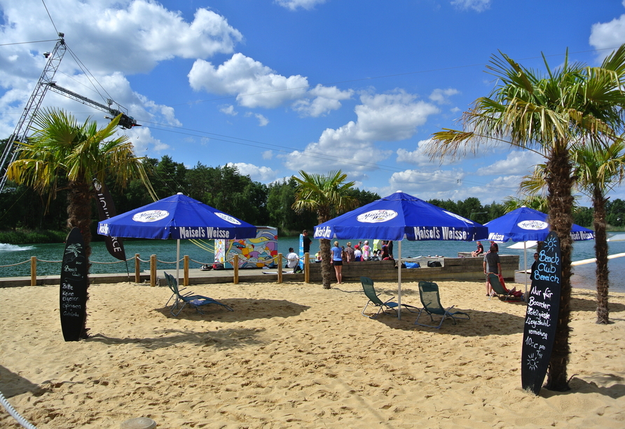 Im Beachclub entspannen Sie unter Palmen und schauen den Wakeboardern auf dem Wasser zu.