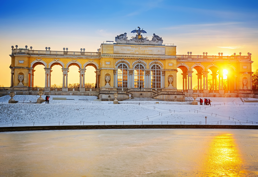 Die Sonne strahlt im Winter durch die Gloriette, welche am Schloss Schönbrunn steht.