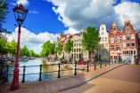 Schlendern Sie in Amsterdam entlang schöner Grachten mit pittoresken Häusern im Hintergrund.