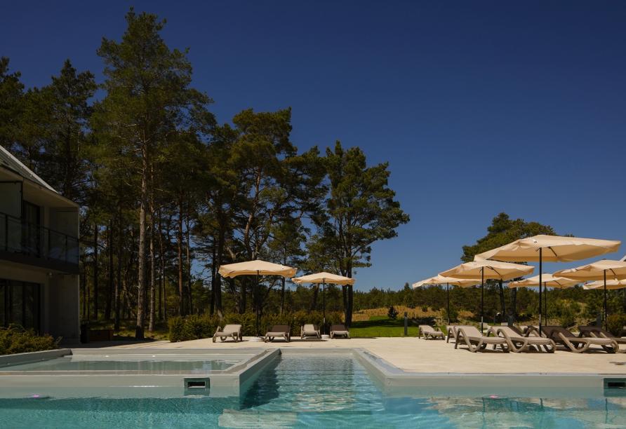 Entspannen Sie am modernen Pool auf den Sonnenliegen.