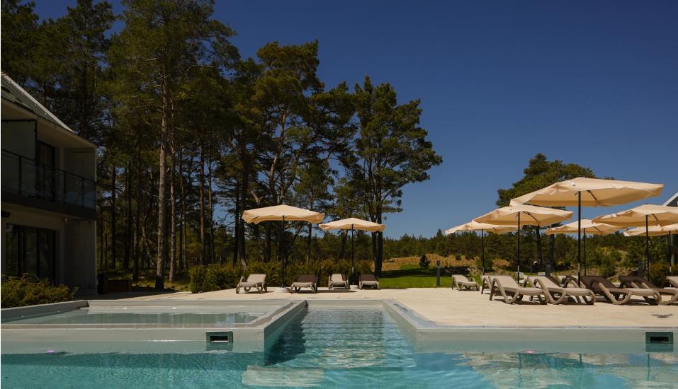 Entspannen Sie am modernen Pool auf den Sonnenliegen.