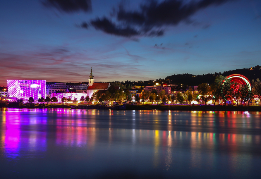 Sie schlendern entlang der Donau und bewundern das Ars Electronica Center (links).