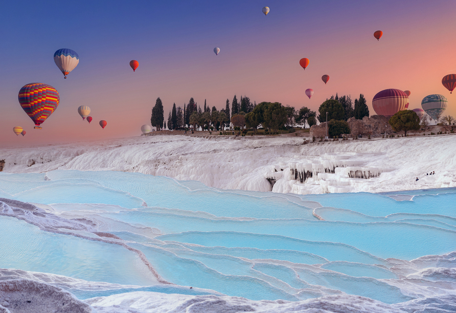 Bei Pamukkale sehen Sie die schneeweißen Kalksinterterrassen – auf Wunsch auch bei einer vor Ort buchbaren Heißluftballonfahrt.