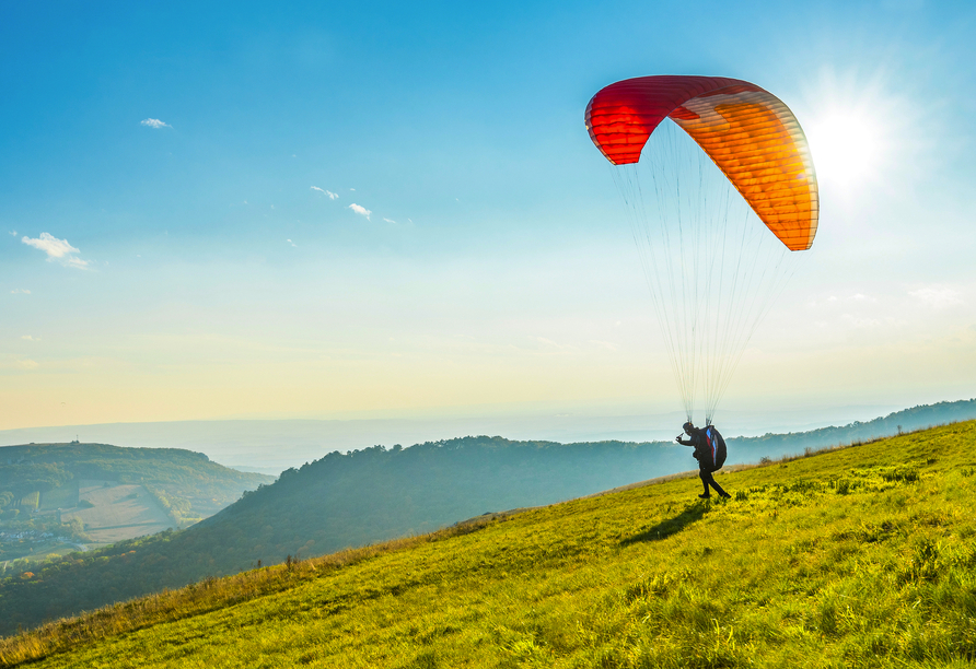 Machen Sie einen Gleitschirmflug und schauen Sie sich die Davoser Berge von oben an.