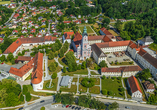 Luftaufnahme des Klosters Aldersbach in Bayern, umgeben von Grünflächen und weiteren Gebäuden.