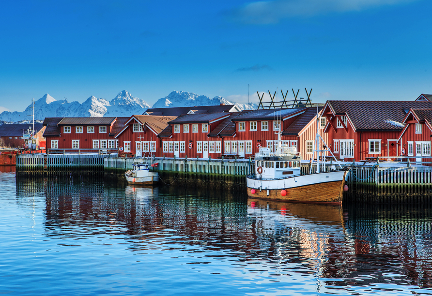 Freuen Sie sich auf malerische Anblicke wie diese typischen roten Fischerhütten im Hafen von Svolvær.