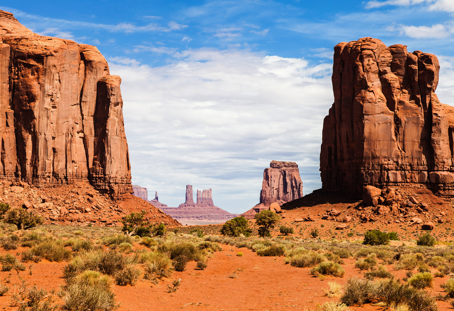Die markanten roten Felsriesen des Monument Valley ragen eindrucksvoll aus der weiten Wüstenlandschaft empor.