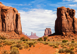 Die markanten roten Felsriesen des Monument Valley ragen eindrucksvoll aus der weiten Wüstenlandschaft empor.