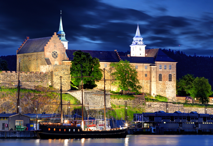 Die mittelalterliche Festung Akershus leuchtet stimmungsvoll in der Nacht.