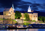 Die mittelalterliche Festung Akershus leuchtet stimmungsvoll in der Nacht.