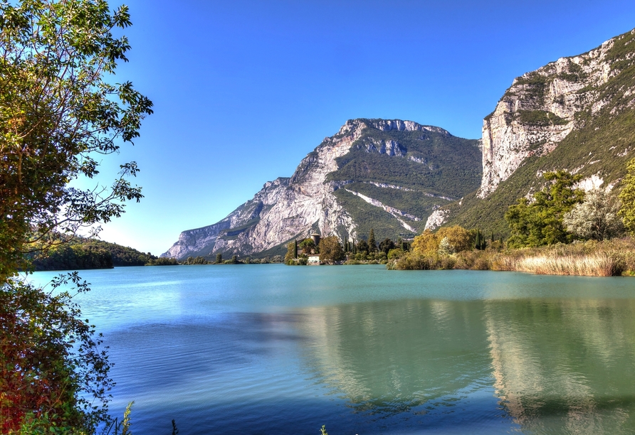 Ein Ort wie aus dem Bilderbuch: Der romantische Lago di Toblino, umgeben von üppiger Natur und Weinbergen.