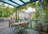 Umgeben von Weinreben sitzen Sie auf der Terrasse.