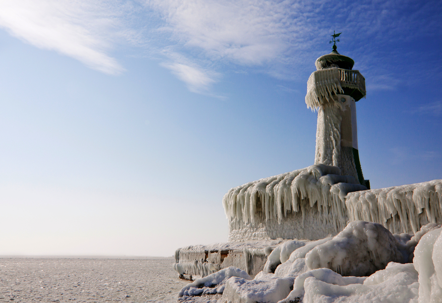 Leuchtturm in Sassnitz auf der Insel Rügen im Winter, umgeben von Eis und Schnee.