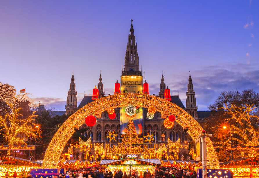 Die Lichter des Christkindlmarkts am Rathausplatz tauchen den Platz in ein warmes Licht.