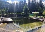 Entspannen Sie in der ruhigen Gartenanlage mit dem idyllischen Naturbadeteich.