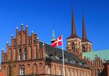 Majestätische Türme, rote Backsteinfassaden und jahrhundertealte Geschichte machen die Kathedrale von Roskilde zu einem eindrucksvollen Wahrzeichen Dänemarks.