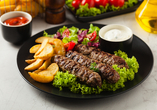 Herzhaft, aromatisch und einfach köstlich – Cevapcici mit knusprigen Kartoffeln und frischem Salat bringen den Geschmack des Balkans auf den Teller.