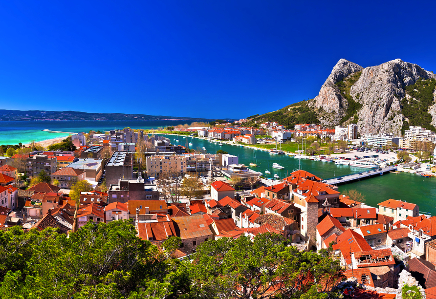 Vor der Kulisse markanter Felsen schmiegt sich die Altstadt von Omiš an das türkis schimmernde Meer und den smaragdgrünen Fluss Cetina, ein Panorama voller mediterraner Lebensfreude.
