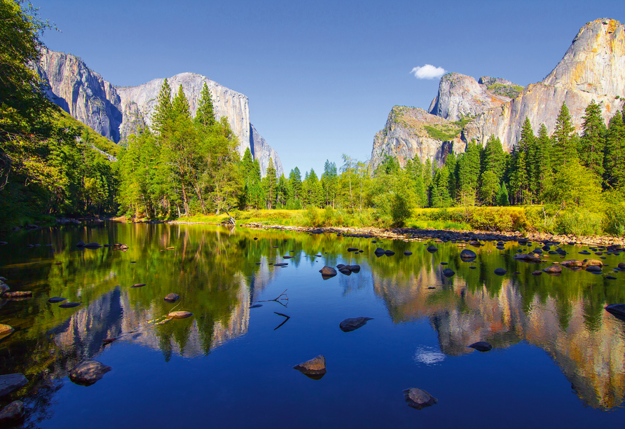 Im Yosemite-Nationalpark in Kalifornien spiegeln sich majestätische Granitfelsen und grüne Wälder im glasklaren Wasser.