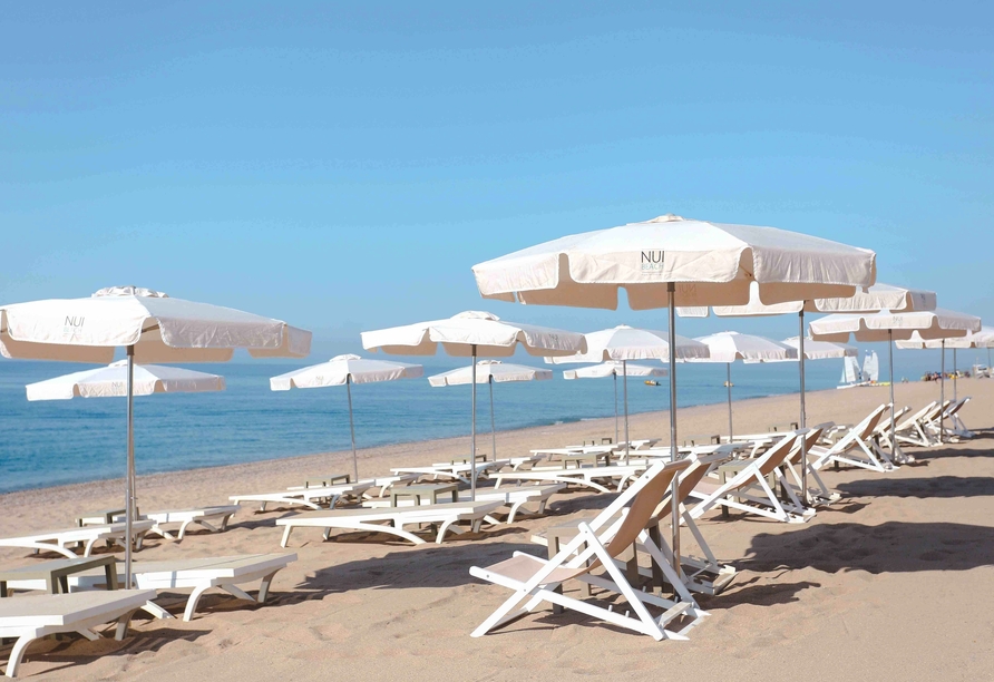 Sonnenschirme, feiner Sand und das glitzernde Meer laden zu entspannten Stunden in Calella ein.