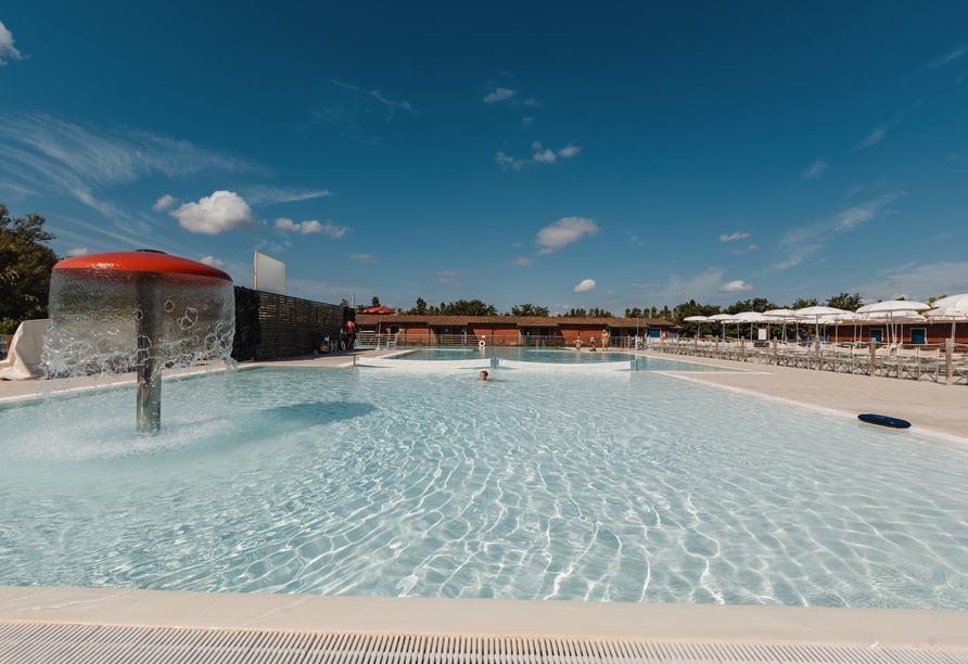 Die großzügige Poollandschaft unter blauem Himmel lädt zum Erfrischungssprung ein.