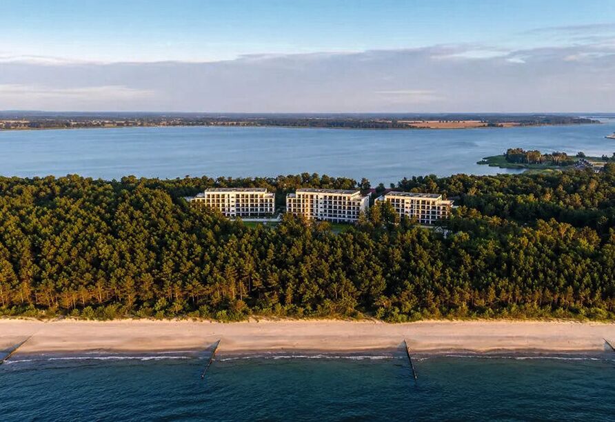 Die Drohnenaufnahme zeigt die besondere Lage des Resorts: Nur rund 60 Meter trennen das Hotel von der Ostsee, während es von dichtem Küstenwald umgeben ist.