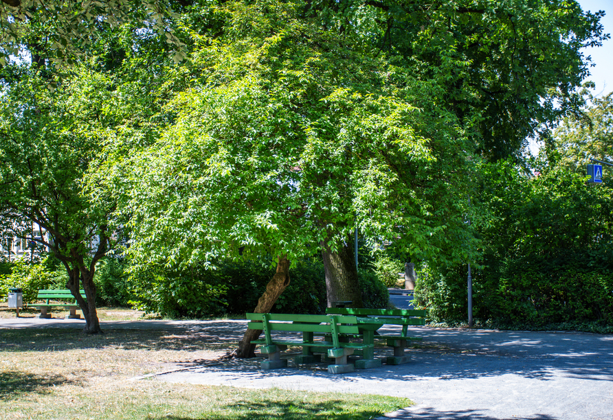 Grüne Wiesen, schattige Bäume und gemütliche Bänke prägen den Stadtpark direkt am Hotel.