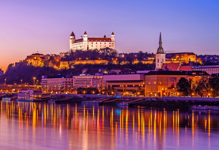 Bestaunen Sie, wie die Burg Bratislava hell erleuchtet über der Stadt thront.