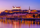 Bestaunen Sie, wie die Burg Bratislava hell erleuchtet über der Stadt thront.