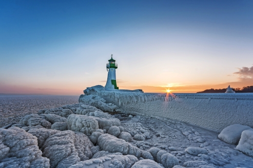 Leuchtturm in Sassnitz auf der Insel Rügen im Winter, umgeben von Eis und Schnee.