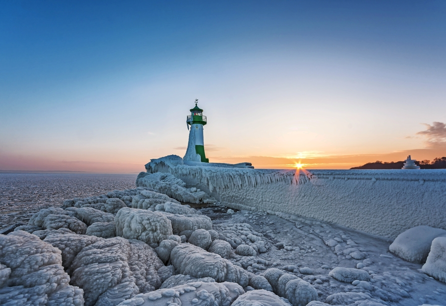 Leuchtturm in Sassnitz auf der Insel Rügen im Winter, umgeben von Eis und Schnee.