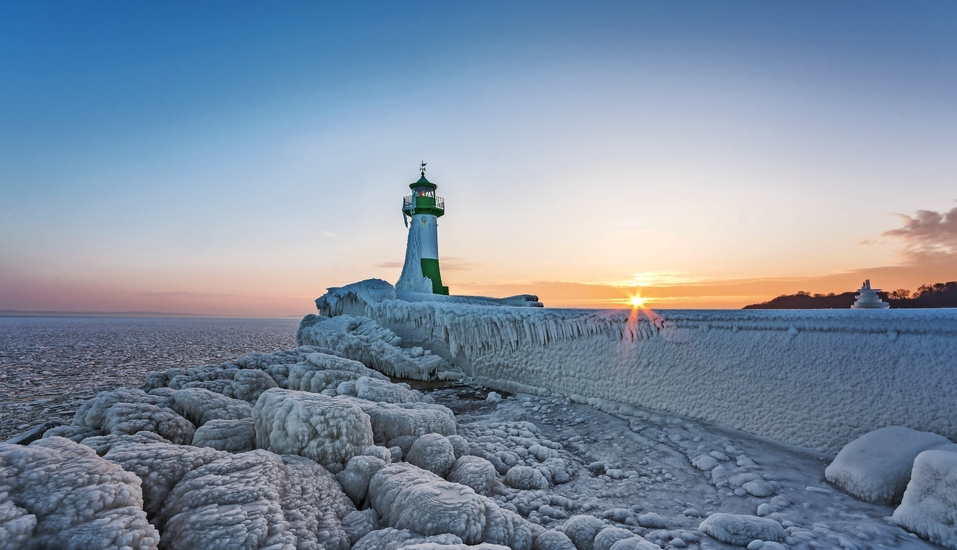Leuchtturm in Sassnitz auf der Insel Rügen im Winter, umgeben von Eis und Schnee.